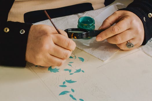 Close-up of artist delicately painting intricate floral patterns using ink.